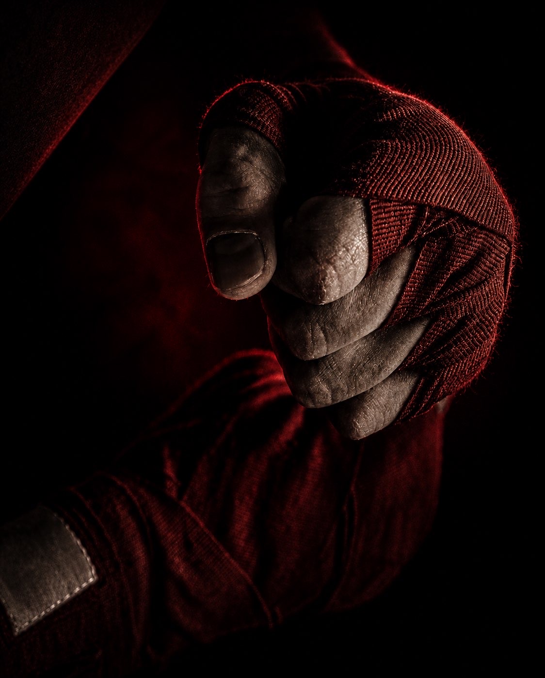 Fighter's clenched fist wrapped in crimson hand wraps